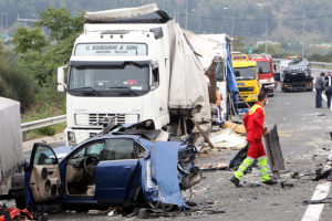 the picture shows a motorway accident involving a large number of trucks and a car. There is a lot of debris spread across the motorway.